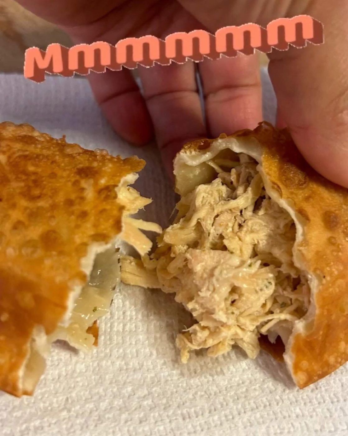 An empanada broken open to show a shredded chicken filling