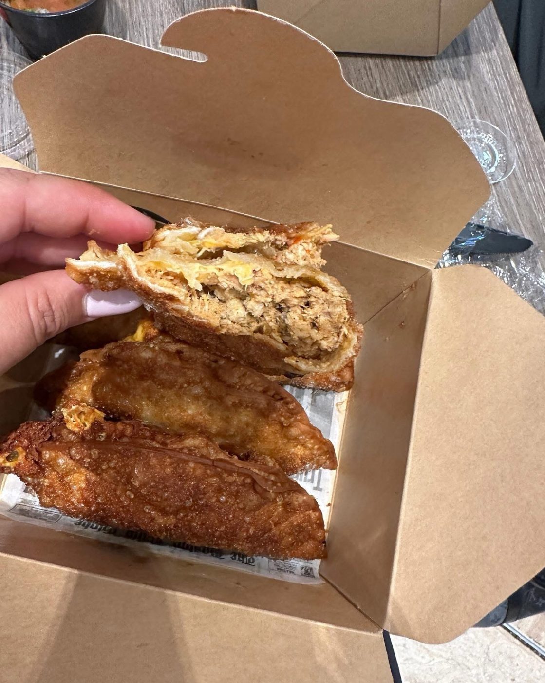 Golden fried empanadas in a kraft takeout box